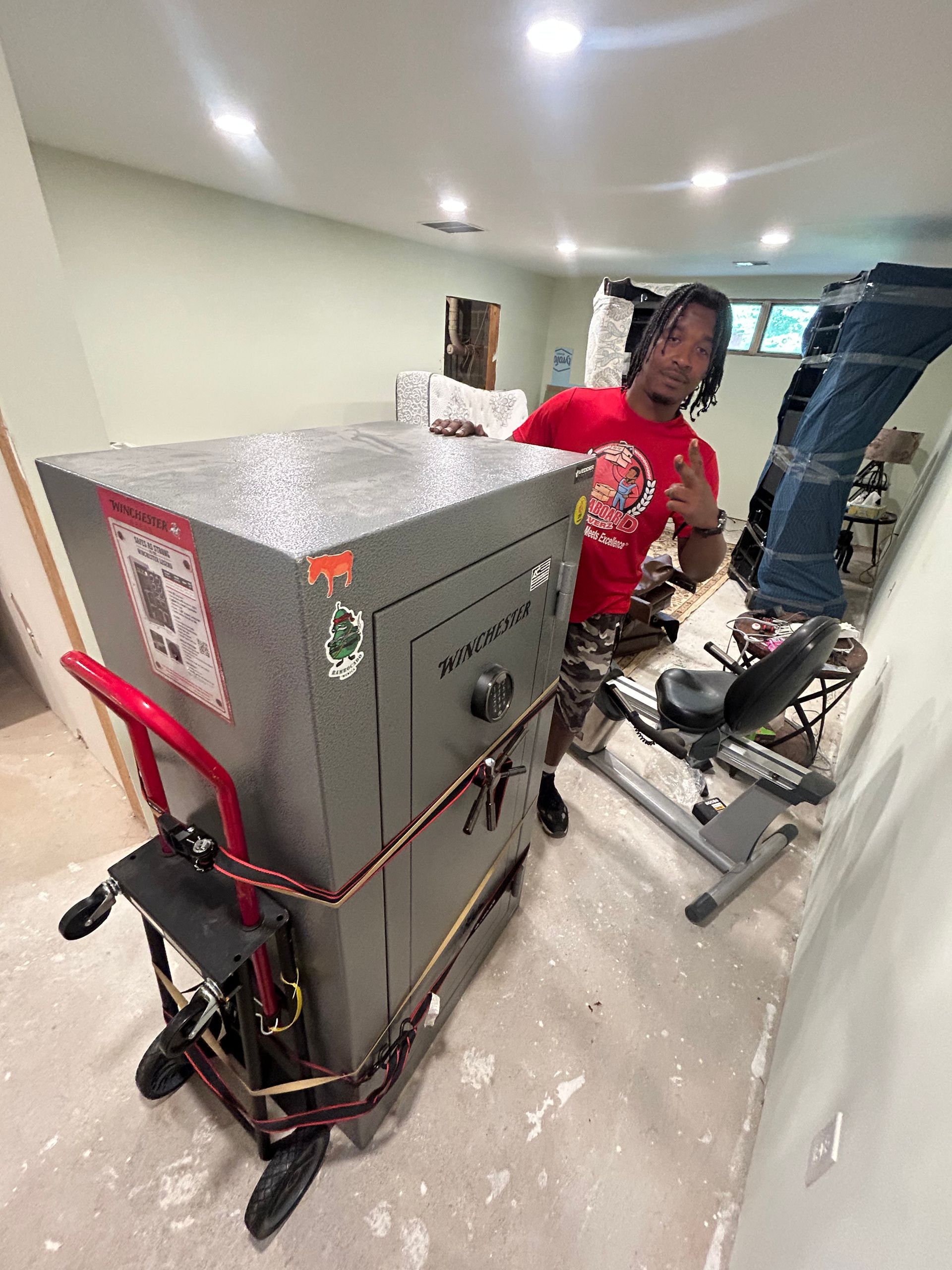 A man is standing next to a large safe on a dolly.