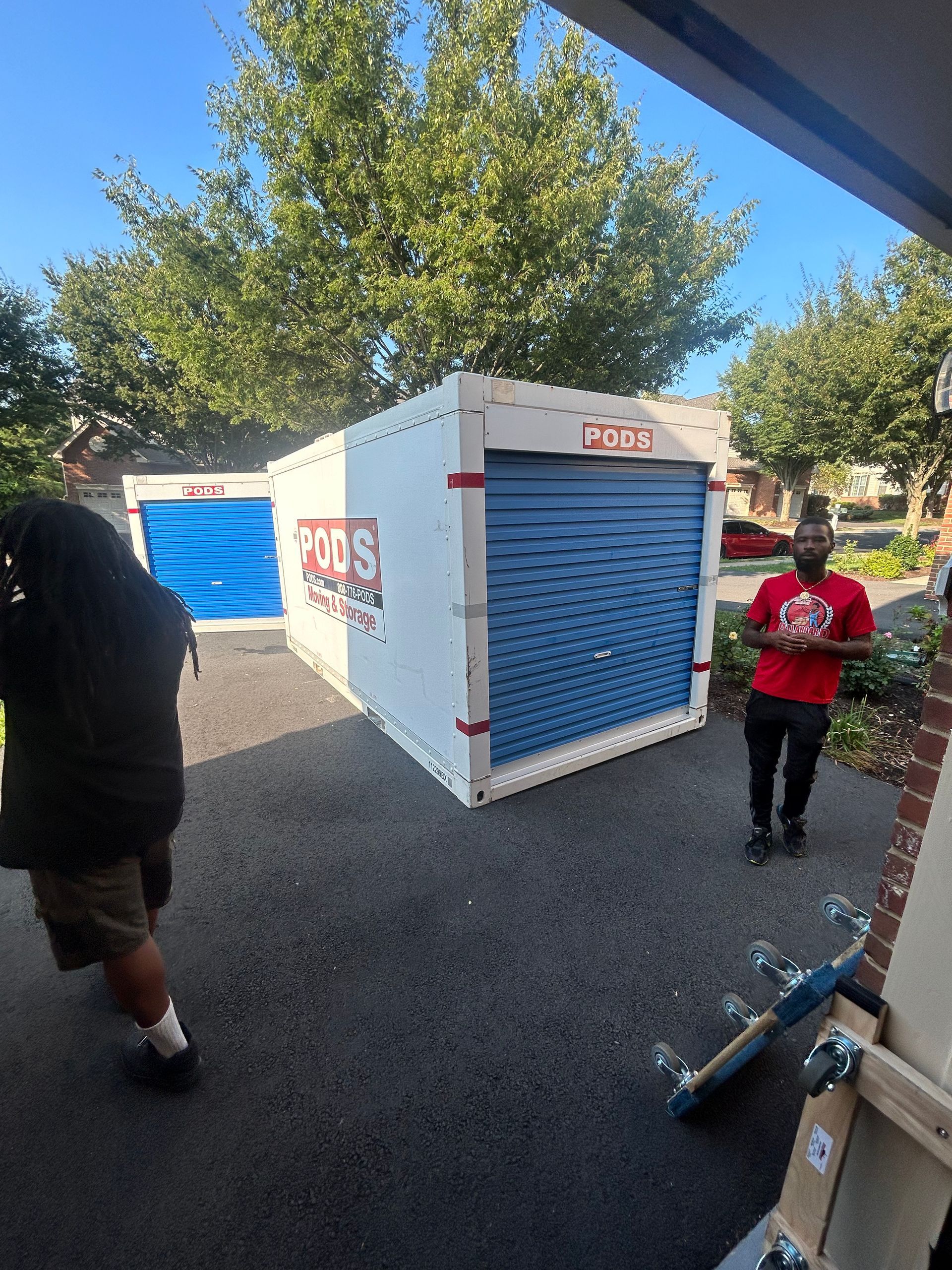 A man in a red shirt is standing in front of a storage unit.