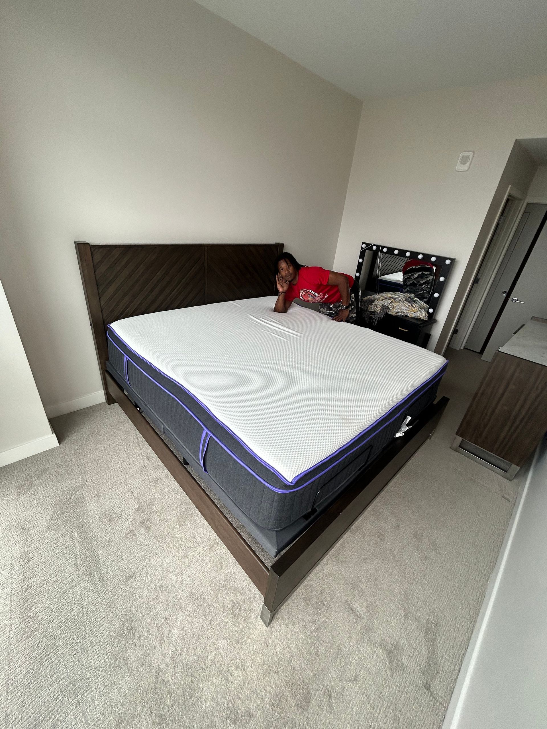A person is laying on a bed with a mattress in a bedroom.