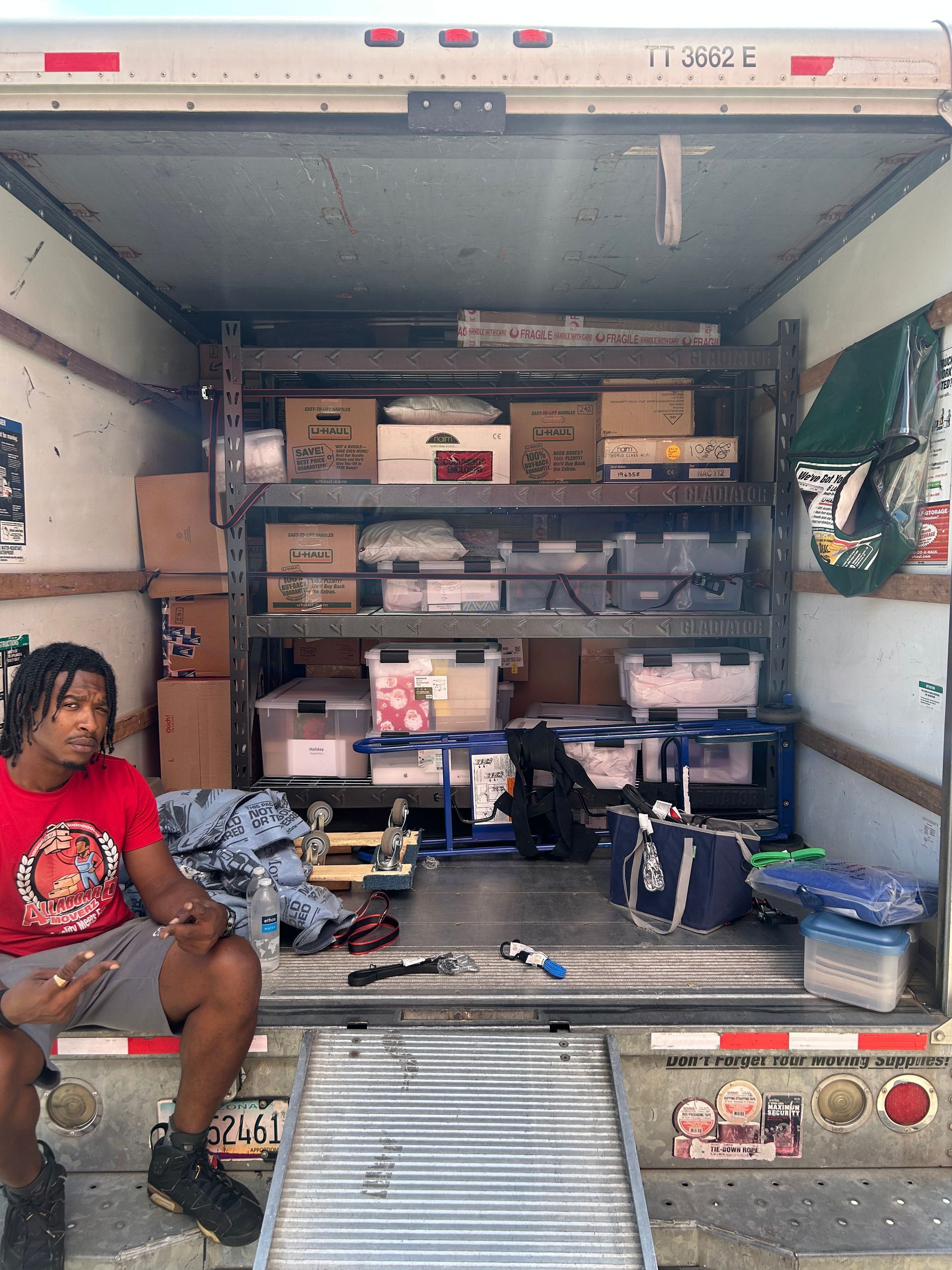 A man is sitting in the back of a moving truck.