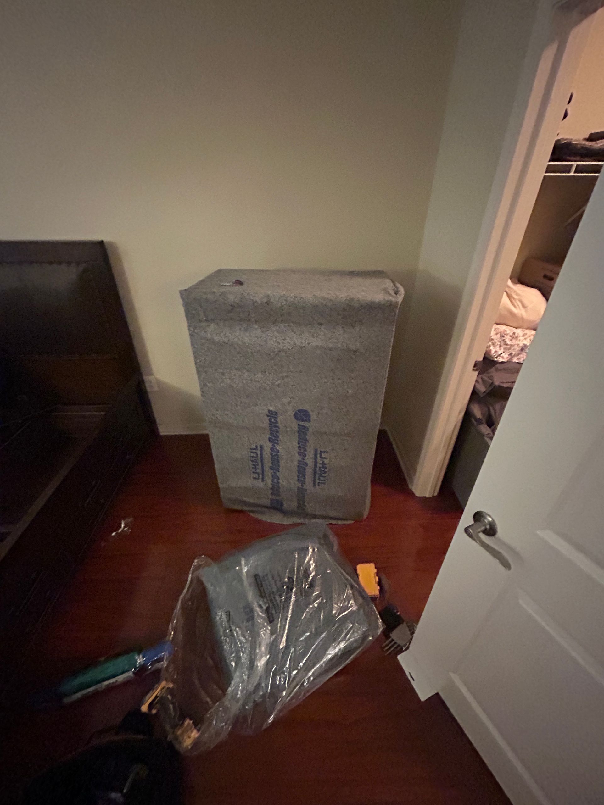 A box wrapped in plastic is sitting in a room next to a door.