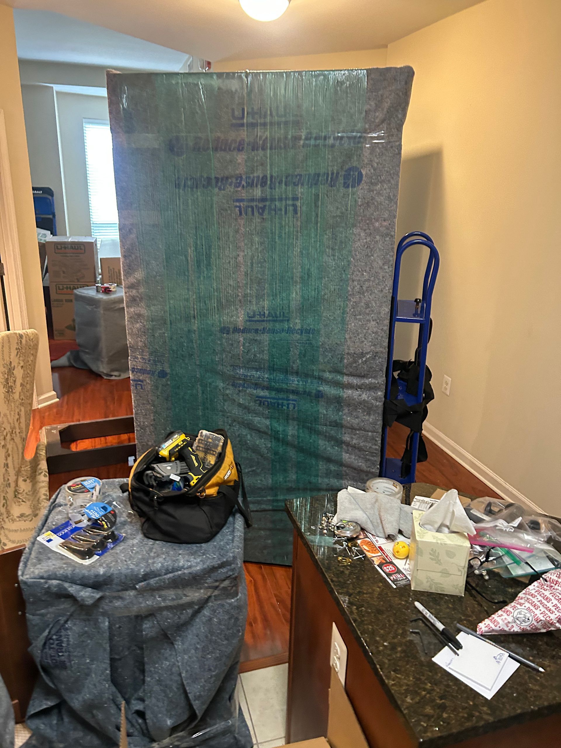 A mattress is wrapped in plastic and sitting on a table in a room.