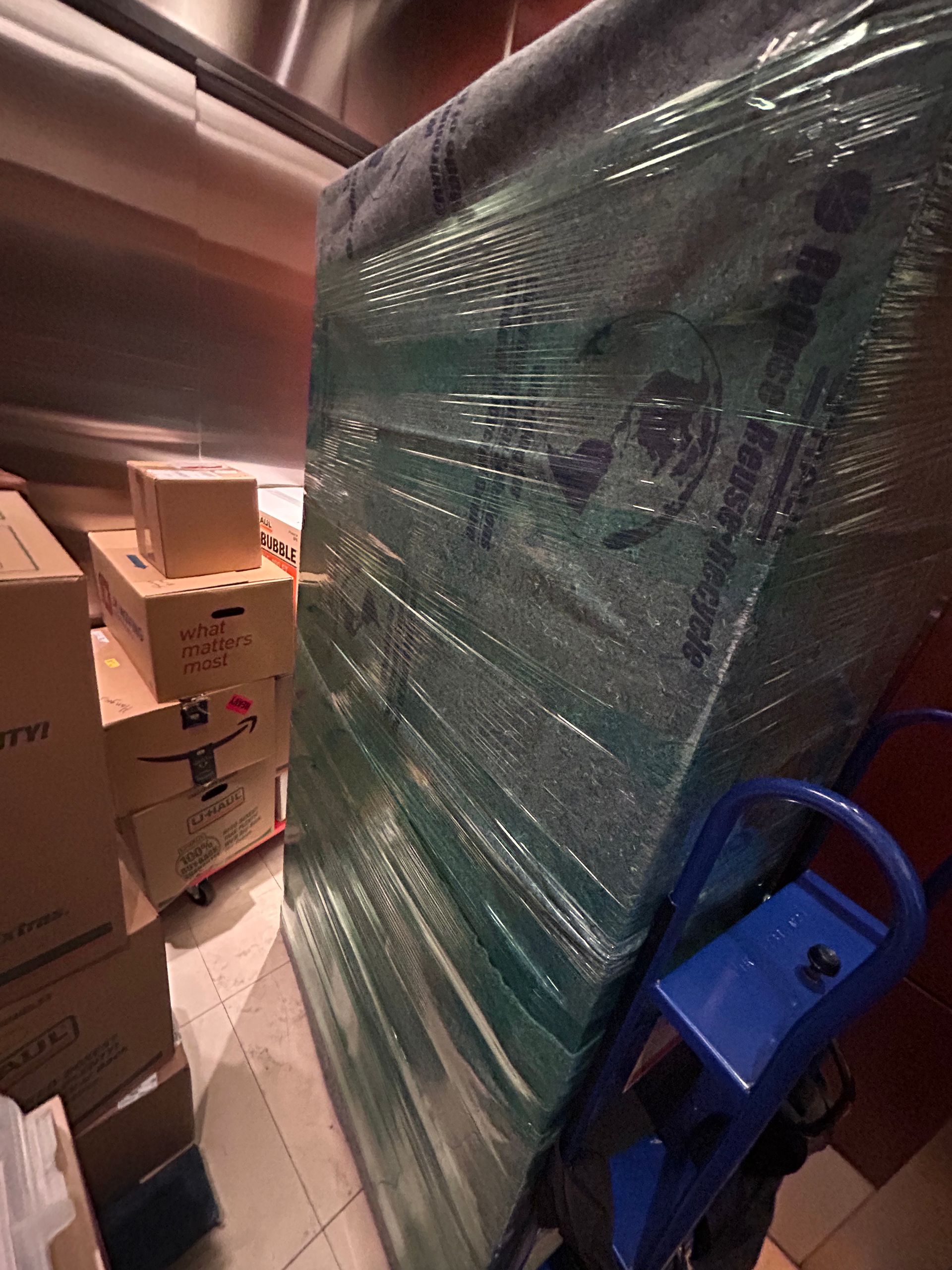 A mattress is wrapped in plastic and stacked on top of each other in a room.