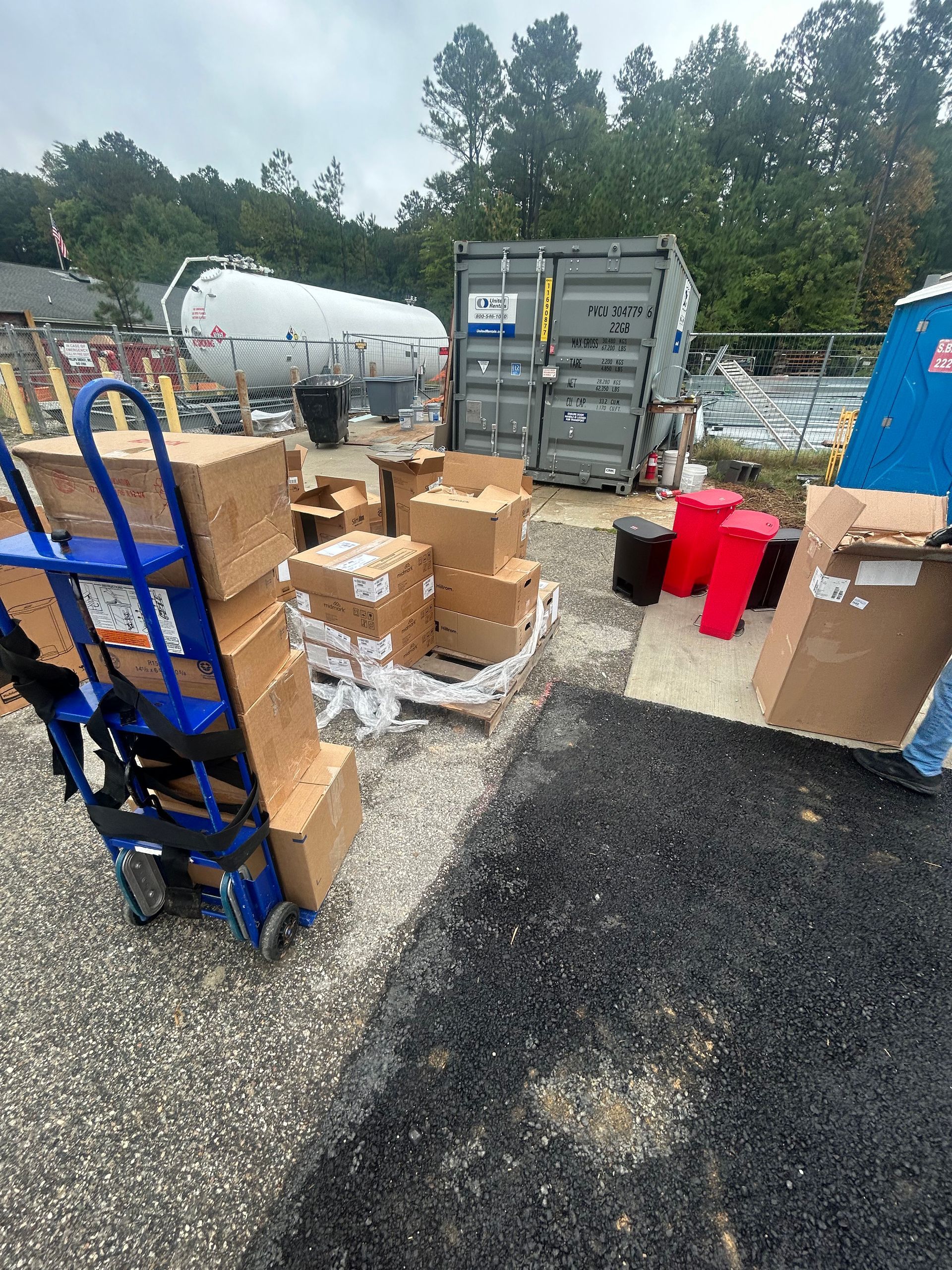 A person is pushing a cart full of boxes in a parking lot.