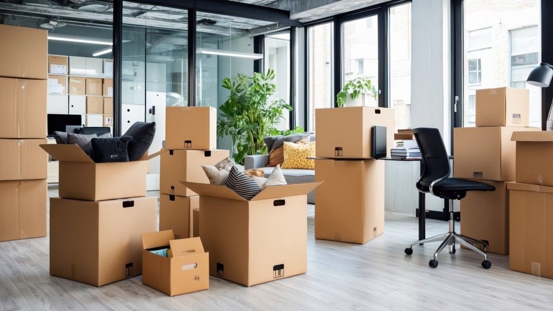 Office space filled with packed cardboard boxes, indicating a move.