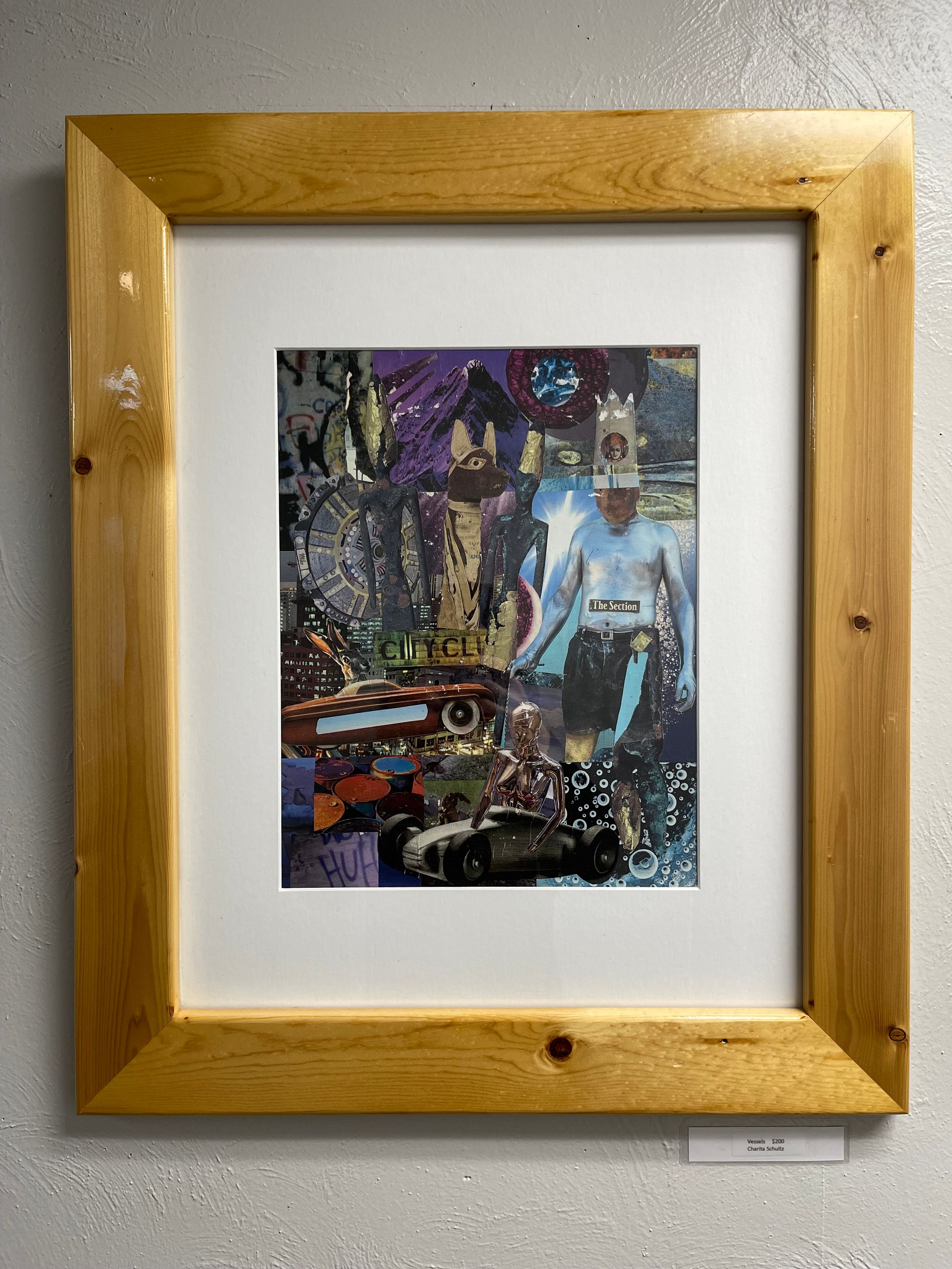 A painting in a wooden frame is hanging on a wall.