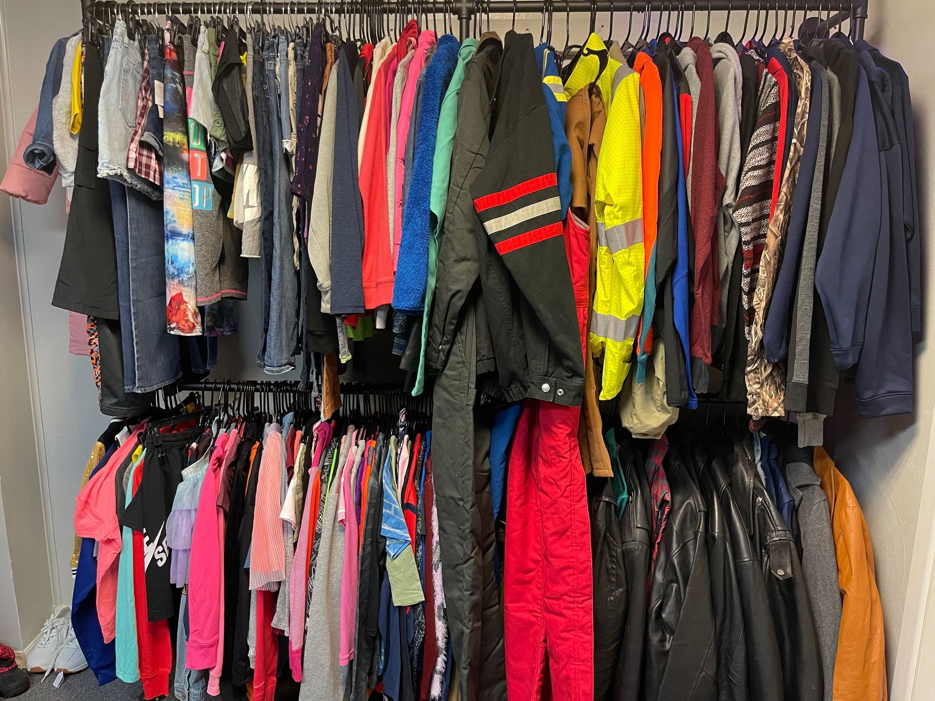 A closet filled with lots of clothes hanging on racks.
