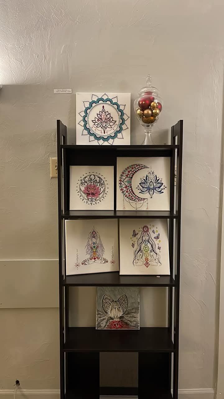 A shelf with paintings on it is sitting next to a wall.