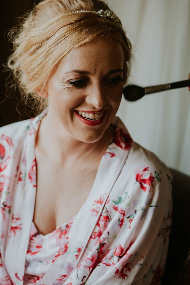 portrait photograph of brode smiling having her makeup done before saddleworth wedding