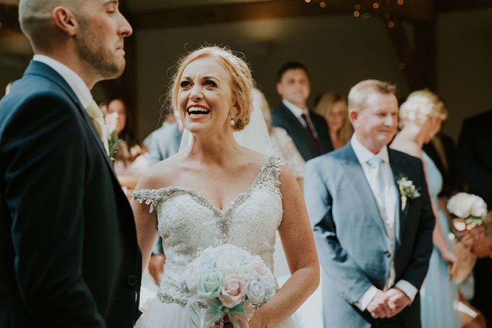 bride at her saddleworth wedding seeing her groom at the end of isle for the first time and smiling