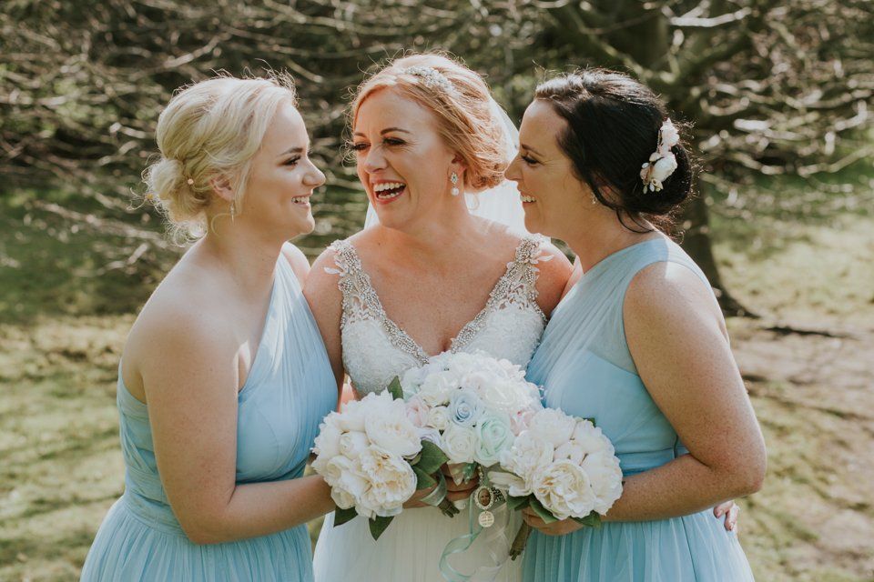 bride and bridesmaids laughing together and looking at each other