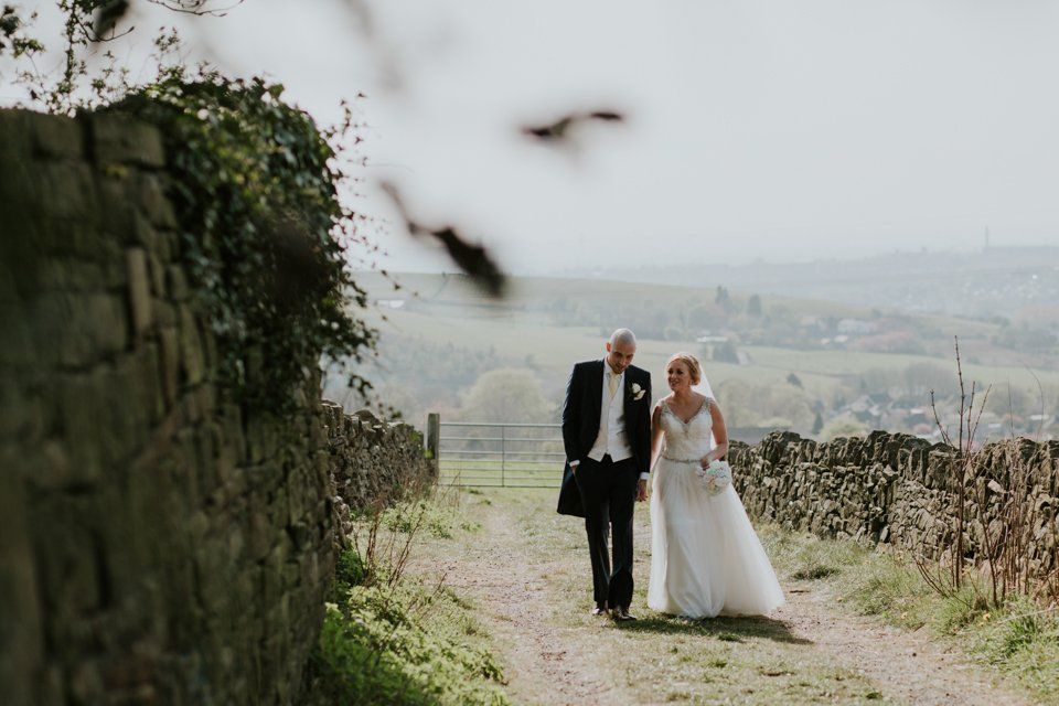 bride and groom walking and holding hands at saddleworth wedding