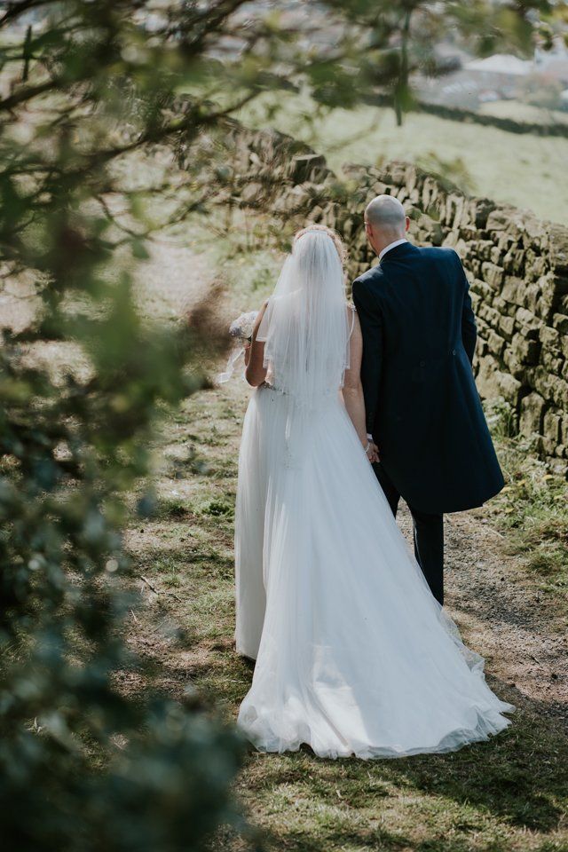back shot of bride and groom walking and holding hands at the white hart lydgate wedding