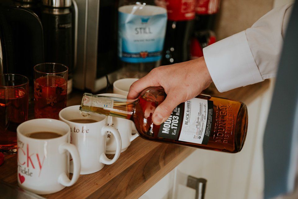 groom poring whisky into cups of coffee the morning of his wedding