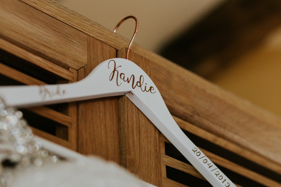 white hanger for a wedding dress with brides name on hung up on cupboard