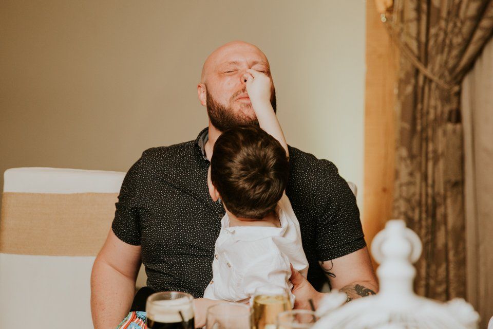man having his nose pinched by his son at a wedding reception