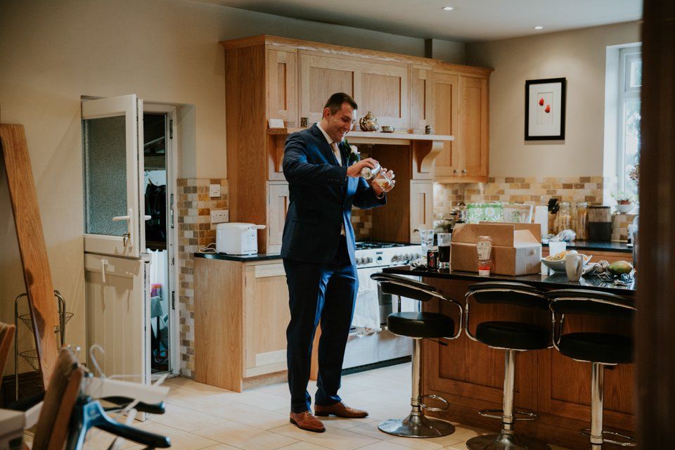 best man pouring a beer whilst getting ready before the wedding