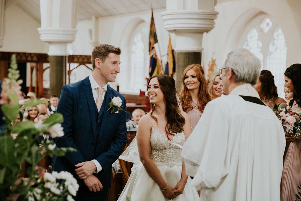 bride and groom standing together laughing at each other on church alter