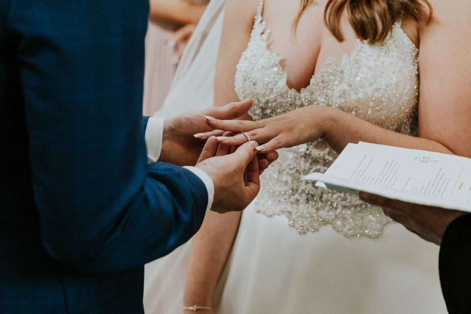 close up photograph of groom putting a ring on his brides finger