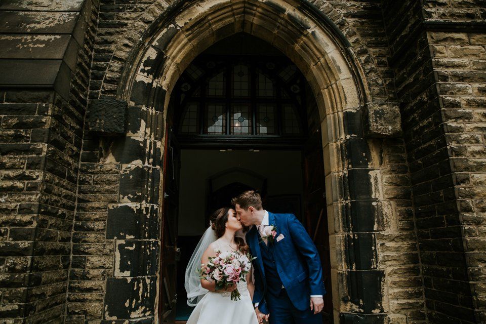 Bride and groom kissing in church doorway