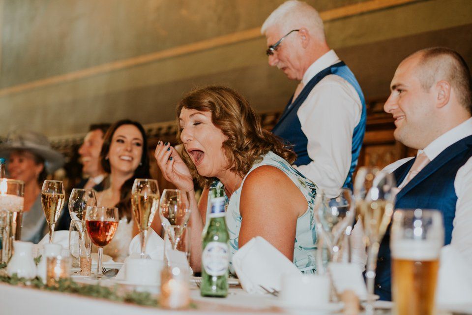 mother of the bride sat laughing on top table at father of the brides wedding speech