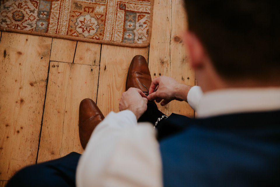groom tying his shoes before leaving the house to get married 