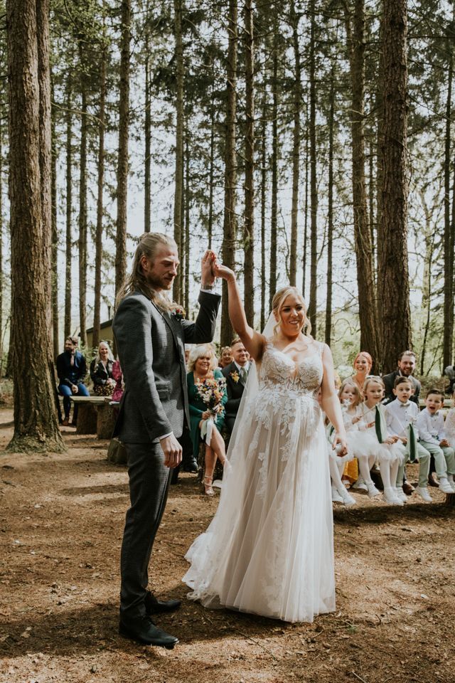 bride and groom cheering at forest wedding