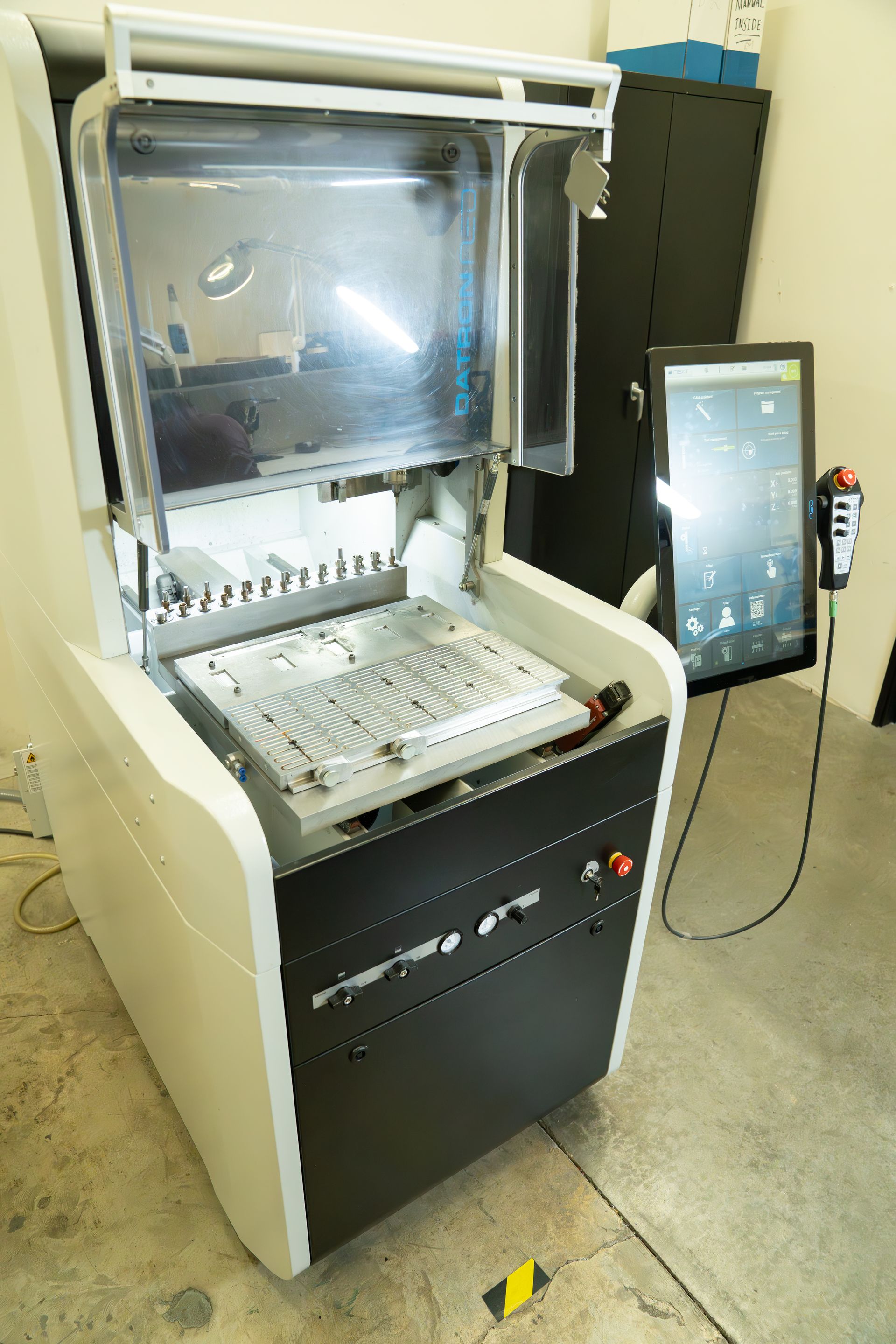 A machine is sitting on the floor in a room with a monitor.