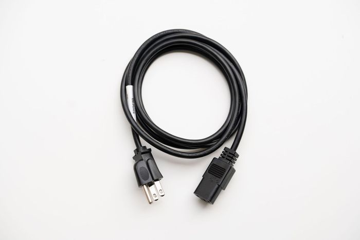 A black power cord is sitting on a white surface.