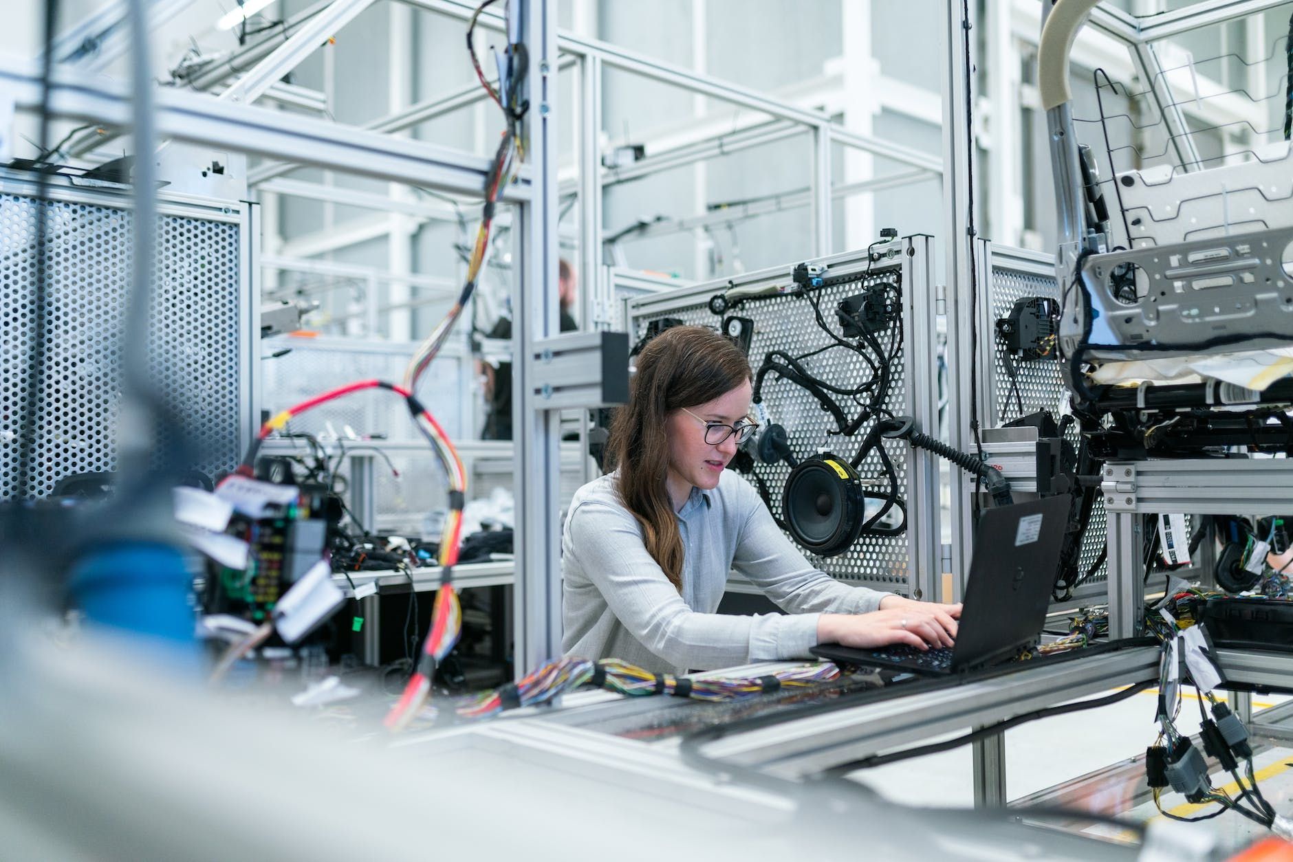 A woman is working on a laptop computer in a factory.