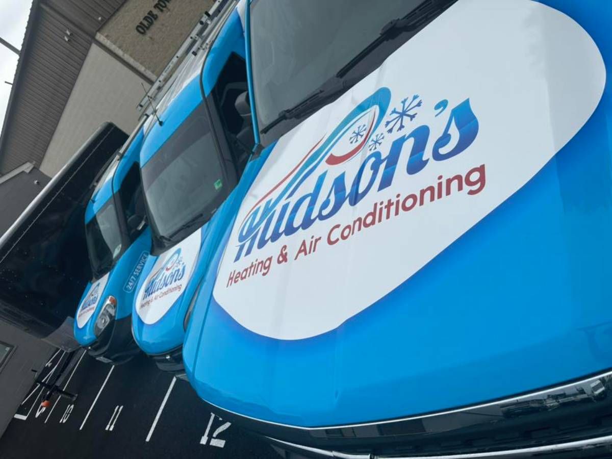 Hudson’s Heating & Air Conditioning - Blue Hudson's Heating & Air Conditioning vans parked, angled view with logo.