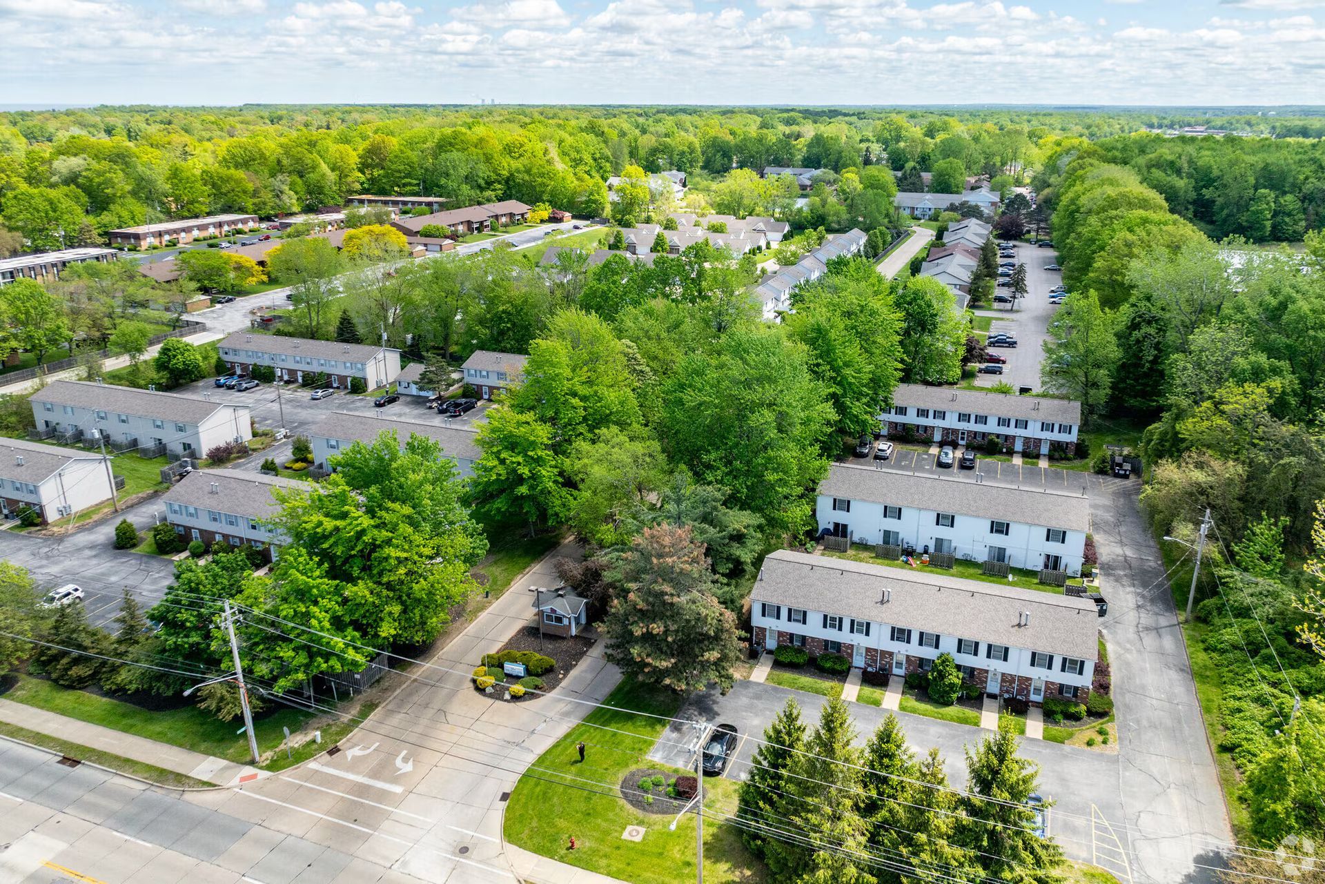 Aerial view of townhouses, green trees, and a road.