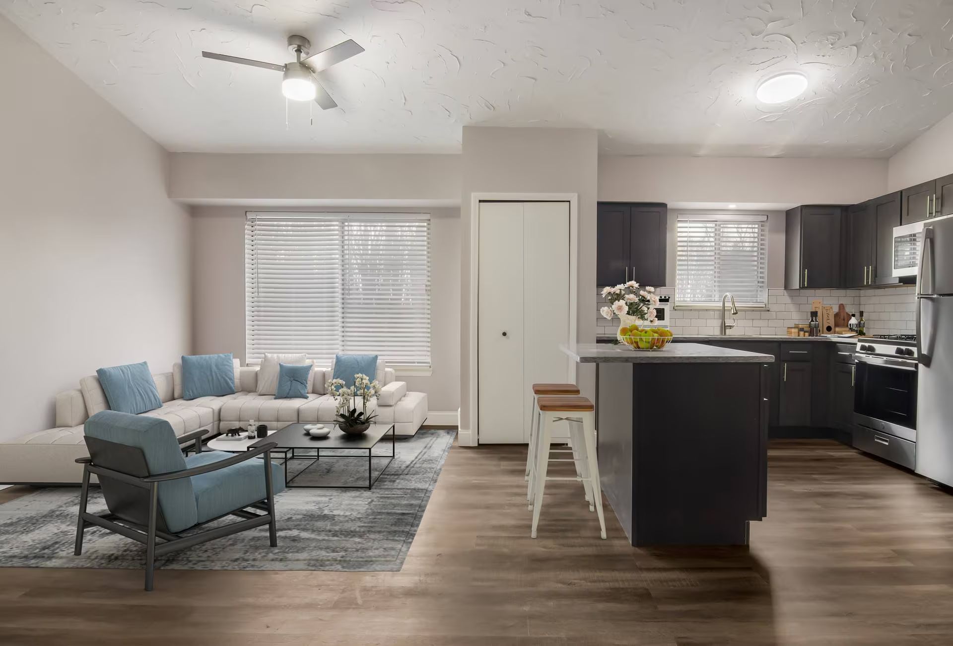 Open-concept living space with a kitchen, living area with blue sectional, and dark gray island.