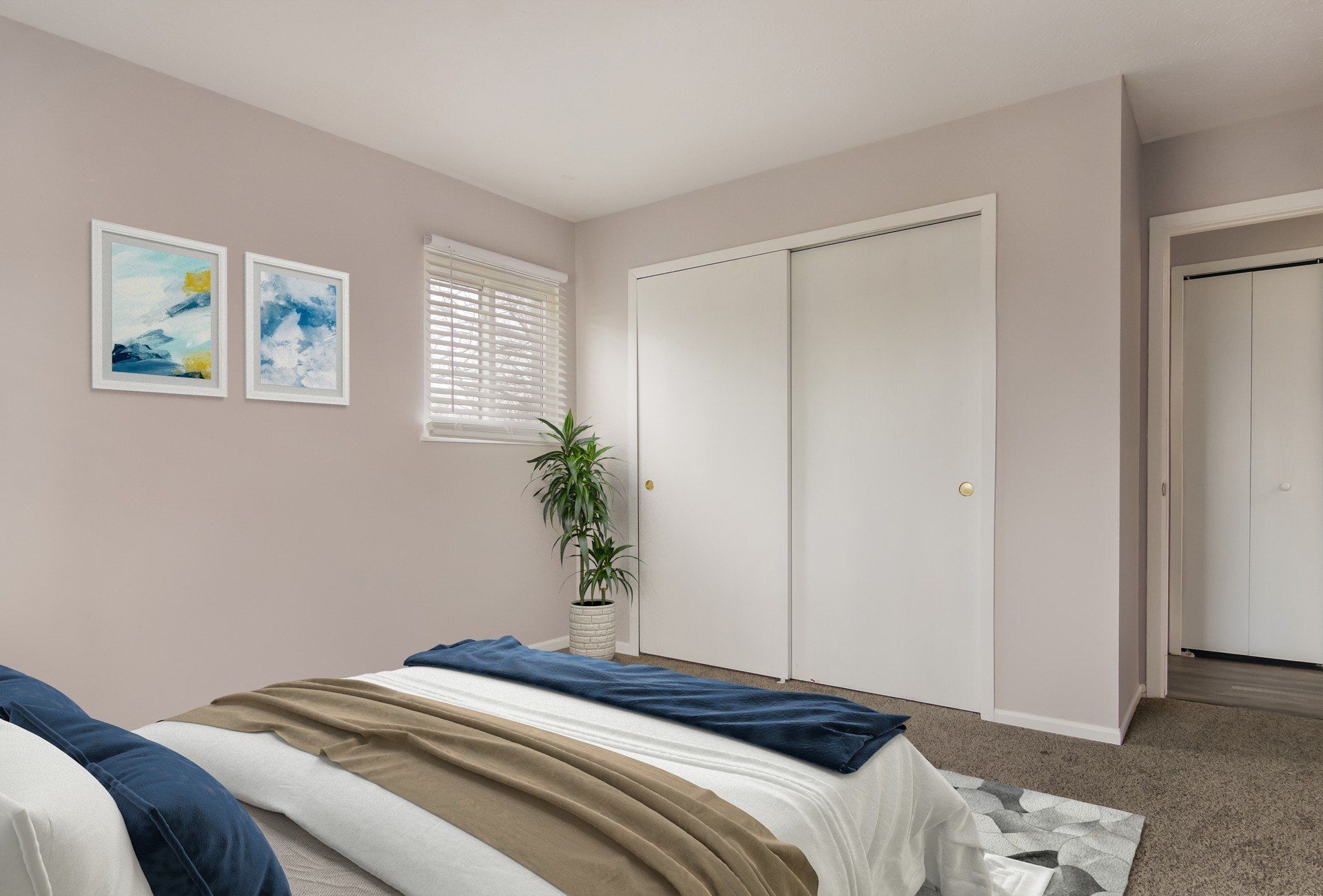 Bedroom with bed, closet, art, window, and plant; neutral colors.