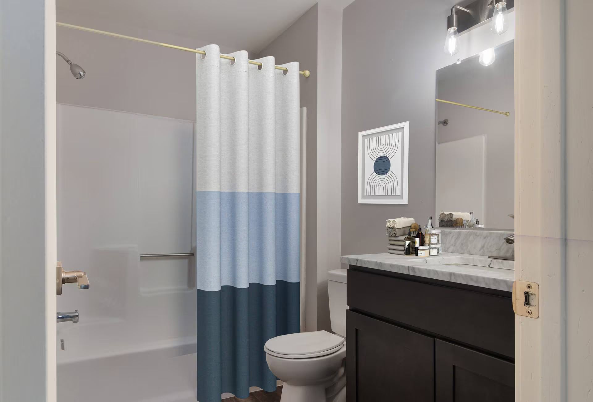 Bathroom with shower, toilet, sink, and dark cabinet. White, blue, and navy shower curtain.