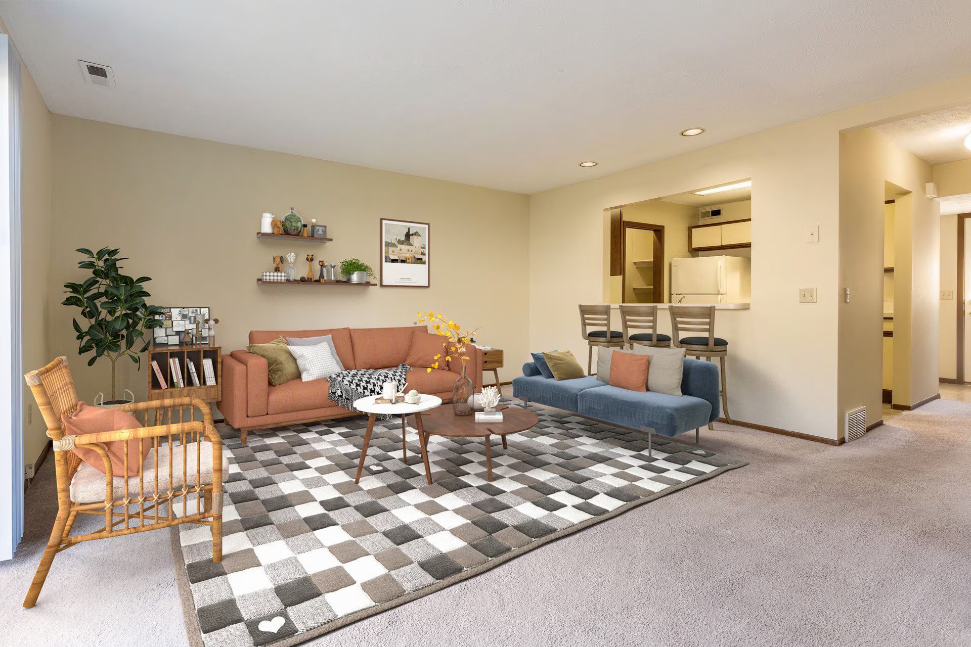 Living room with sofa, chair, rug, and kitchen opening. Beige walls, neutral colors.