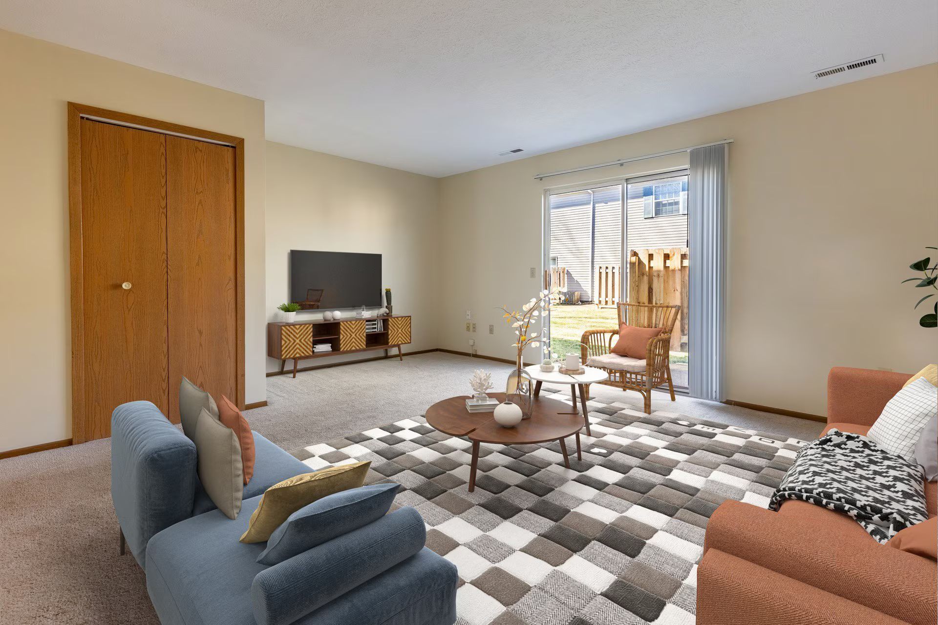 Living room with blue and orange couches, TV, coffee table, and door to a yard.