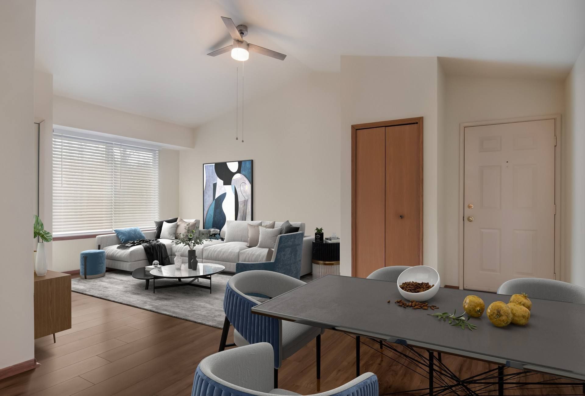 Living room with dining area. Gray sectional, modern dining table, abstract artwork, dark wood floors.