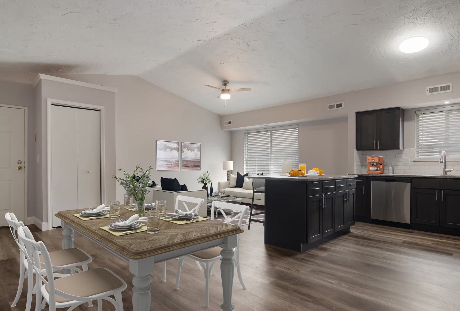Open-concept living space with dining area, kitchen island, and living room; neutral colors, hardwood floors.