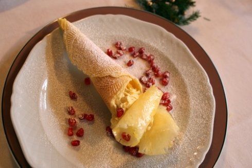 Piatto da dessert con cono gelato, fette di ananas e semi di melograno.