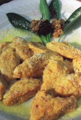 Primo piano di gnocchi dorati e fritti, guarniti con foglie di salvia, frutti di bosco e formaggio grattugiato.