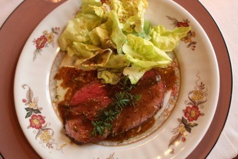 Bistecca con salsa e lattuga su un piatto floreale.