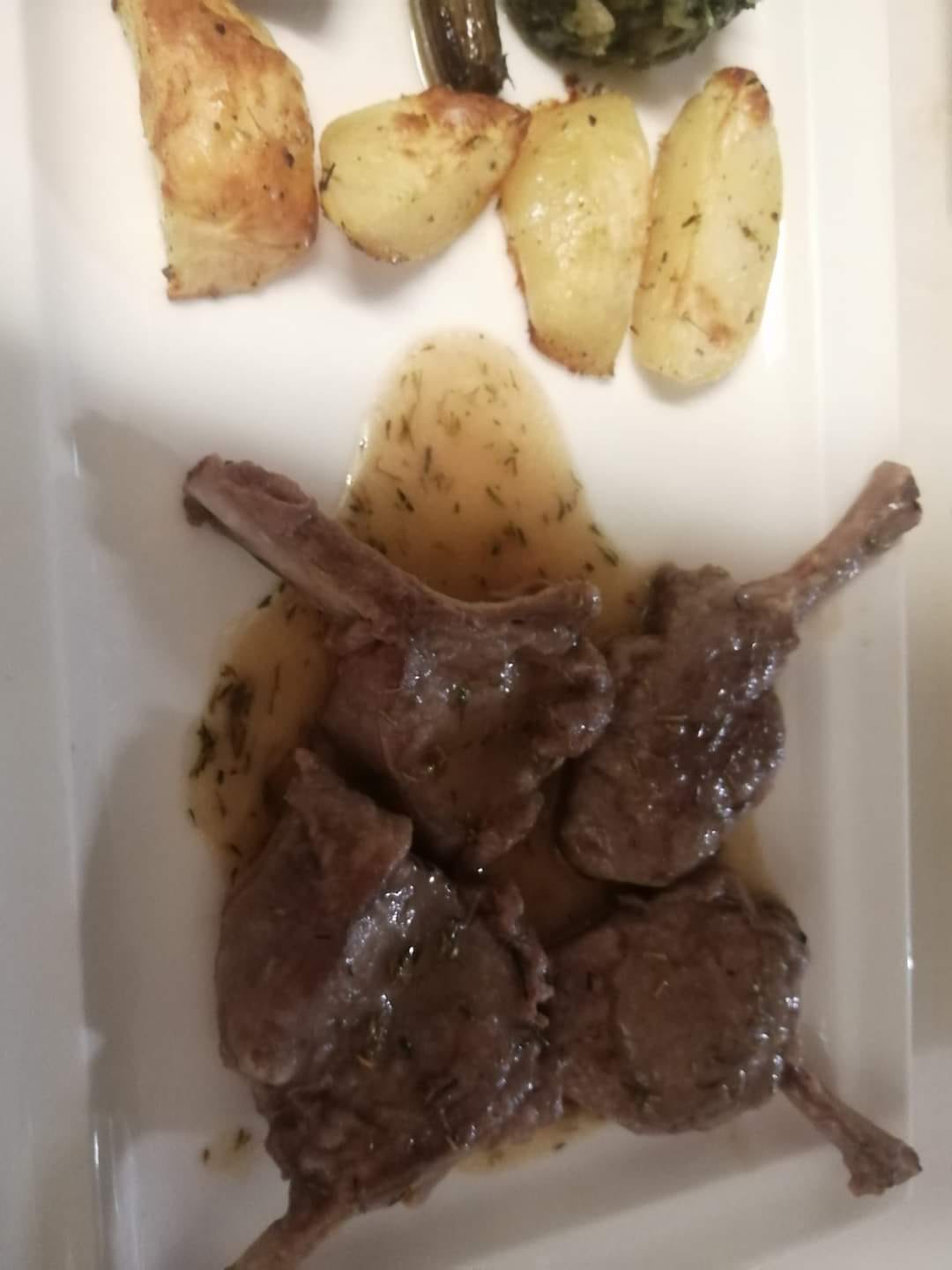 Costolette di agnello in salsa con patate arrosto.