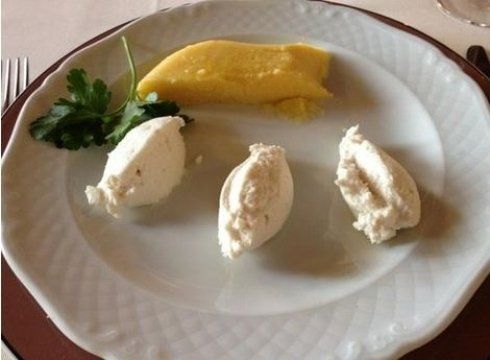 Piatto con polenta gialla, tre cucchiaiate di formaggio bianco e guarnizione di prezzemolo.