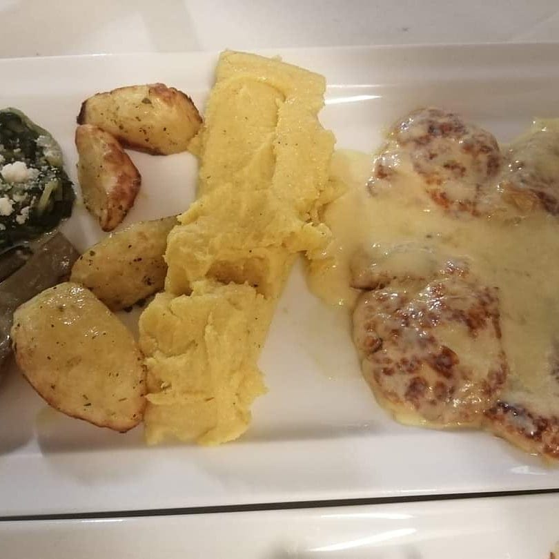 Piatto di cibo: patate, polenta, carne al sugo e spinaci.
