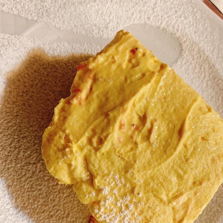 Torta soufflé gialla su un piatto bianco spolverata di zucchero a velo.