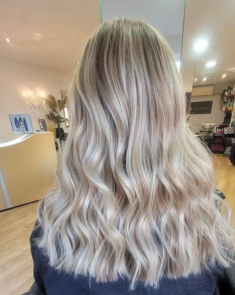 A woman with blonde hair is sitting in a chair in a salon.