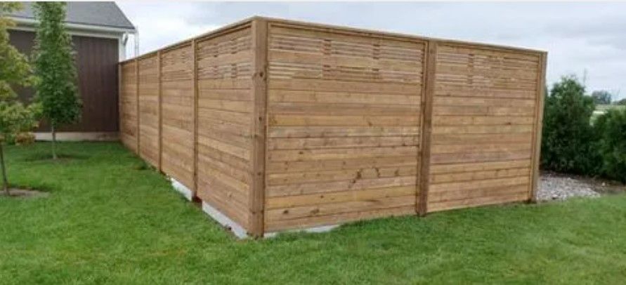 Wooden privacy fence on a grassy lawn; house visible in the background.