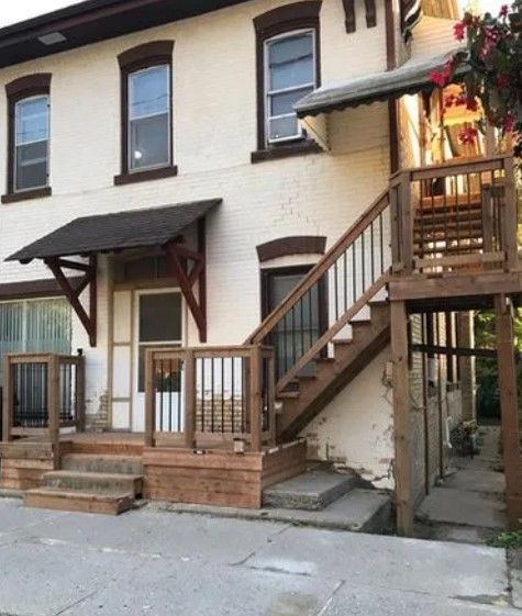 Two-story brick building with exterior wooden stairs and decks. Brown trim, awning, and railings.