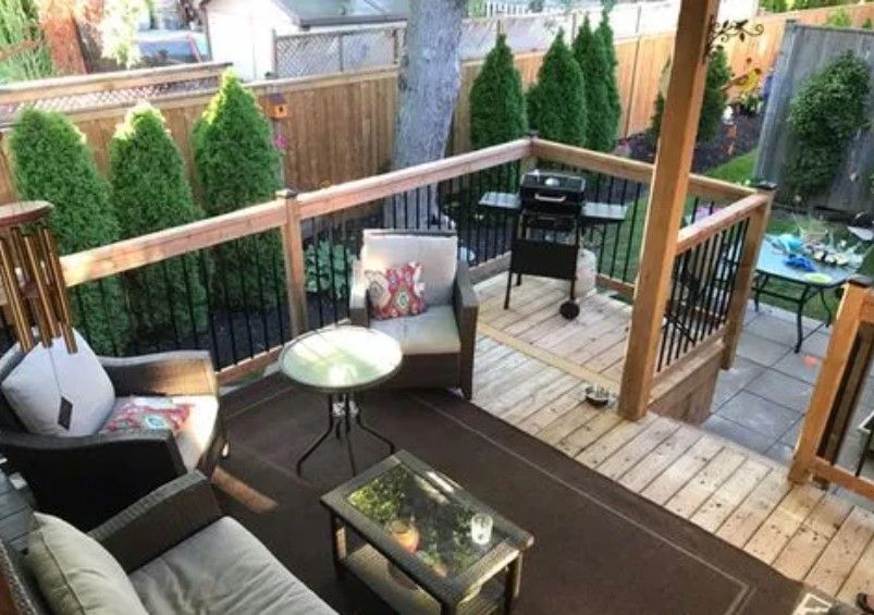 Wooden deck with patio furniture, a grill, and evergreen trees in the background.